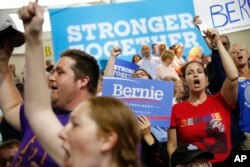 Supporters for Democratic presidential candidates Hillary Clinton and Sen. Bernie Sanders, I-Vt. cheer before a rally in Portsmouth, N.H., Tuesday, July 12, 2016