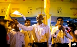 Maldives' opposition presidential candidate Ibrahim Mohamed Solih, center, shakes hands with a supporter as his running mate, Faisal Naseem, right, addresses the gathering in Male, Maldives, Monday, Sept. 24, 2018.