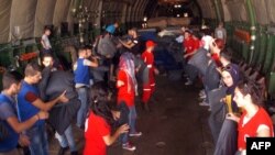 A handout picture released by the Syrian Arab News Agency on Sept. 12, 2015, shows members of the Syrian Red Crescent unloading a Russian plane carrying humanitarian aid on the tarmac of the Martyr Bassil al-Assad international airport in Latakia.