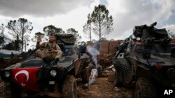 ទាហាន​តួកគី​ម្នាក់​លើក​ដៃ​នៅ​ពេល​ឈរ​ជើង​នៅ​លើ​ទួល Bursayah នៅ​ក្នុង​ស្រុក Afrin ប្រទេស​ស៊ីរី កាលពី​ថ្ងៃទី៣ ខែមីនា ឆ្នាំ២០១៨។