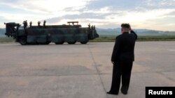 북한 김정은 국무위원장이 지난 9월 화성-12 발사 현장에서 발사 성공에 환호하는 북한군 지도부에 손을 흔들고 있다.