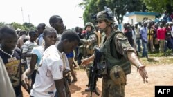 Des soldats français de l'opération Sangaris discutent avec des Centrafricains à l'entrée de l'aéroport de Bangui, République Centrafircaine le 12 décembre 2013.