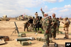 Iraqi army soldiers and volunteers, such as Iranian-backed Shiite militias and Sunni tribes, prepare to launch mortar shells and rockets against Islamic State militant positions outside Tikrit, March 4, 2015.