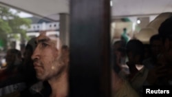 Seorang pria dari etnis Hazara melihat keluar dari belakang panel kaca di tempat penampungan sementara di Karawang, Jawa Barat. (Foto: Dok)