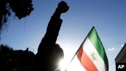 FILE - A demonstrator shouts near the flag of the former Imperial State of Iran during a protest by supporters of the National Council of Resistance of Iran, outside Tehran's embassy in Rome, in 2017. The group said Sept. 9, 2024, that its Stockholm offices had been firebombed.
