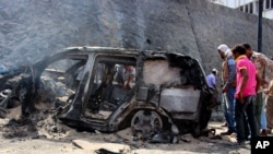 Yemenis inspect the scene of a car bomb attack that killed a Yemeni senior official in the southern port city of Aden, Yemen, Sunday, Dec. 6, 2015. A huge explosion killed the governor of Yemen's southern Aden province and six of his bodyguards.