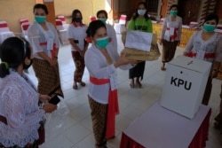 Petugas pemilu memakai masker pelindung saat pemilihan kepala daerah di Denpasar, Provinsi Bali, 9 Desember 2020. (Foto: Antara/Fikri Yusuf via REUTERS