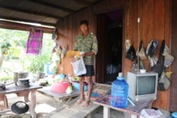 លោក កែវ ឡេងគី អាយុ៤១ឆ្នាំ កសិករ ក្នុងឃុំអន្លង់វិល ខេត្តពោធិ៍សាត់ ដើរចេញពីក្នុងផ្ទះកាន់ឯកសារកម្ចីមីក្រូហិរញ្ញវត្ថុ កាលពីថ្ងៃទី៨ ខែវិច្ឆិកា ឆ្នាំ២០២០។ (ស៊ុន ណារិន/វីអូអេ)