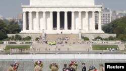 FILE - Soldiers dressed in WWII uniforms place wreaths in front of the Freedom Wall, with the Lincoln Memorial in the background, at the World War II Memorial in Washington, May 8, 2015.
