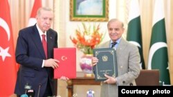 তুরস্কের প্রেসিডেন্ট রেচেপ তাইয়েপ এরদোয়ান (বামে) ও পাকিস্তানের প্রধানমন্ত্রী শাহবাজ শরিফ পাকিস্তান-তুরস্ক হাই লেভেল স্ট্র্যাটেজিক কোঅপারেশন পরিষদে একটি যৌথ ঘোষণাপত্রের প্রতিলিপি ধরে রয়েছেন। ইসলামাবাদ। ফটোঃ ১৩ ফেব্রুয়ারি, ২০২৫। (তথ্য ও সম্প্রচার মন্ত্রণালয়, পাকিস্তান)