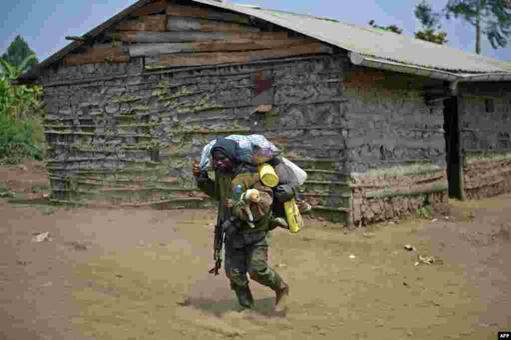 Seorang tentara Kongo, sambil membawa seekor anjing, berjalan melalui desa Rusayo di pinggiran kota Goma, yang sehari sebelumnya merupakan lokasi bentrokan pasukan Kongo dengan pemberontak M23. 