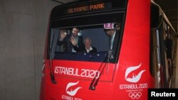 International Olympic Committee (IOC) Vice President and chairman of the IOC Evaluation Commission Craig Reedie (2nd L), and Hasan Arat, leader of the Istanbul 2020 Bid Committee (L), wave from a metro train in Istanbul March 24, 2013.