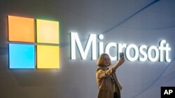 FILE - A visitor takes a photo at the Microsoft stand at Mobile World Congress 2024 in Barcelona, Spain, Feb. 27, 2024. New European Union rules aimed at preventing tech companies from dominating digital markets will change what people see online starting March 7, 2024.