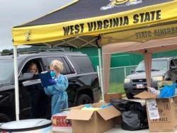 Parents and students arrive in their vehicles for health screenings and temperature checks before moving into residence halls at West Virginia State University campus, July 31, 2020, in Institute, West Virginia.