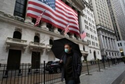 A man wearing a mask walks by the New York Stock Exchange, March 17, 2020.