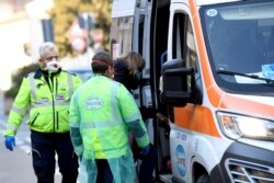 Medics wearing protective masks take a woman into an ambulance amid fears of the coronavirus outbreak spreading from China to other countries, in Casalpusterlengo, northern Italy, Feb. 22, 2020.