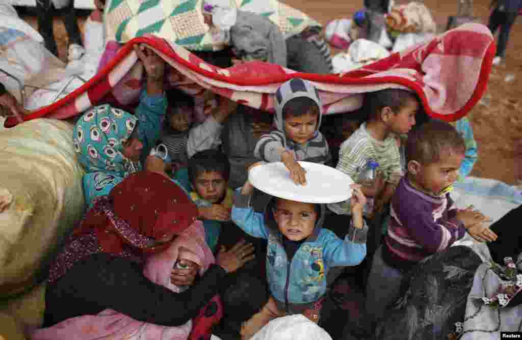 Syrian Kurdish refugees cover themselves from rain after crossing into Turkey from the Syrian border town Kobani, Oct. 2, 2014.