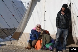 A refugee family waits to leave Presevo, Serbia, for Western Europe, Jan. 19, 2016. (P. Walter Wellman/VOA)