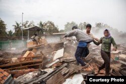 ២៤ មករា ២០០៩ ភ្នំពេញ កម្ពុជា៖ អ្នកភូមិ​រត់​គេច​ពី​យានយន្ត​ឈូស​ដី​ដែល​បាន​សម្រុក​ចូល​ឈូស​បំណែក​សេស​សល់​ពី​ផ្ទះ​សម្បែង​ដែល​ត្រូវ​បំផ្លាញក្នុង​អំឡុង​ពេល​ការជម្លៀស​ប្រជាជន​ដោយ​បង្ខំ​ពី​សហគមន៍​ដី​ក្រហម។ ​© Nicolas Axelrod / Ruom