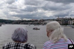 Two women watch a rescue vessel off the Margit bridge on the Danube river where a sightseeing boat had capsized in Budapest, Hungary, May 31, 2019.