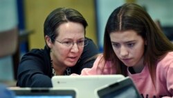 FILE - A teacher librarian at a Connecticut high school, left, works with a student in a Digital Student class, Dec. 20, 2017. The required class teaches media literacy skills and has the students scrutinize sources for their on-line information.