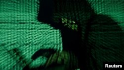 A man holds a laptop computer as cyber code is projected on him in this illustration picture taken on May 13, 2017. 