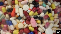 FILE - Prescription drugs fill a glass flask at the state crime lab in Taylorsville, Utah, July 6, 2017. Attorneys general from more than 40 states are alleging the nation's largest generic drug manufacturers conspired to artificially inflate and manipula