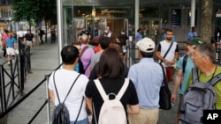 FILE - Visitors holding tickets line up at the entrance to the National September 11 Memorial and Museum in New York, July 11, 2017.
