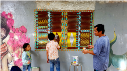 រូបឯកសារ៖ លោក​ ស្រី​ បណ្តូល ក្នុងពេលរៀបចំគូរគំនូរពណ៌លើផ្ទាំងជញ្ជែងអគារមួយ ក្នុងបរិវេណអង្គការហ្វារពន្លឺសិល្បៈ។ (រូបថតផ្តល់ឲ្យដោយហ្វារពន្លឺសិល្បៈ)