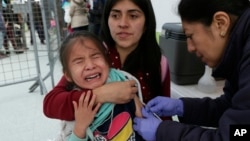 A Venezuelan girl cries while receiving a measles vaccine at an immigration processing office on the Rumichaca bridge, after crossing the border from Colombia to Ecuador, June 13, 2019.