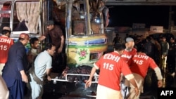 Pakistani volunteers and local residents move the body of a blast victim from a bus after a bomb on it expoded on the outskirts of Quetta, Pakistan, on Oct. 19, 2015.