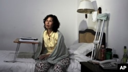 FILE - Ni Yulan sits on a bed in a hotel in Beijing. 