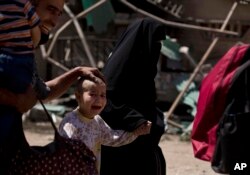 Devojčica obrijane glave, uz svog oca, plače dok njena porodica beži iz dela grada al-Rifai, dok se iračke specijalne jedinice bore protiv Islamske države u zapadnom Mosulu, Irak, 17 maj 2017.