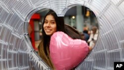 Karina Sosa, 15, of Asuncion Paraguay, poses for a photograph at "Window to the Heart," a Valentine's Day themed art installation in Times Square, Thursday, Feb. 1, 2018, in New York. (AP Photo/Kathy Willens)