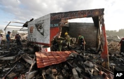 FILE - Firefighters and rescue workers remove debris from the scorched ground of Mexico's best-known fireworks market after an explosion explosion ripped through it, in Tultepec, on the outskirts of Mexico City, Mexico, Dec. 20, 2016.