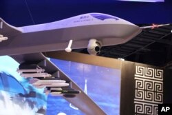 A model of a Wing Loong II weaponized drone hangs above the stand for the China National Aero-Technology Import & Export Corp. at a military drone conference in Abu Dhabi, United Arab Emirates, Feb. 25, 2018.