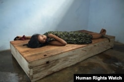 Perempuan berusia 24 tahun berbaring di bale-bale dengan pergelangan tangan dan kaki yang dirantai di pusat penyembuhan Bina Lestari di Brebes, Jawa Tengah. (Human Rights Watch/Andrea Star Reese)