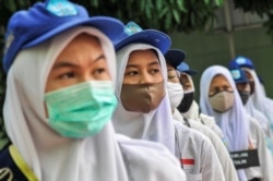 Siswa terlihat mengenakan masker pelindung wajah setelah pemerintah Indonesia membuka kembali sekolah dengan menerapkan proses pembelajaran tatap muka di tengah wabah Covid-19 di Bekasi, di pinggiran Jakarta, 13 Juli 2020. (Foto: Antara/Fakhri Hermansyah/