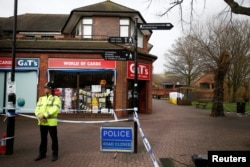 FILE - A police officer stands at a cordon around the bench where former Russian intelligence agent Sergei Skripal and his daughter Yulia were found after they were poisoned, in Salisbury, Britain, March 11, 2018.