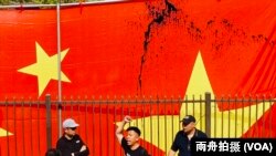 来自香港的萧运军在被泼墨的中华人民共和国国旗前