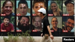 Seorang pria melintas di depan poster Hersh Goldberg-Polin bersama poster sandera lainnya yang diculik dalam serangan Hamas pada 7 Oktober, di Tel Aviv, Israel, 1 September 2024. (Foto: REUTERS/Florion Goga)