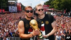 Dua pemain sepakbola nasional Jerman, Mario Goetze (kiri) dan Andre Schuerrle dalam upacara kemenangan dekat Gerbang Brandenburg Gate, Berlin, Juli 2014. 
