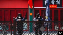 FILE - Security guards browse their smartphones near shuttered business shops in Beijing, China, Feb. 23, 2020.