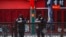 FILE - Security guards browse their smartphones near shuttered business shops in Beijing, China, Feb. 23, 2020.