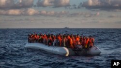 Pengungsi dan kaum migran dari kawasan sub-Sahara dalam perahu yang kelebihan muatan menunggu untuk diselamatkan oleh LSM Spanyol, Proactiva Open Arms (19/7). Utara Sabratha, dekat Libya. (foto: AP Photo/Santi Palacios)