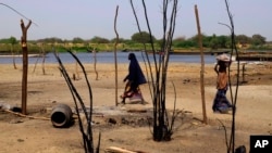 Des femmes tchadiennes passent devant des maisons détruites à la suite d'une attaque de Boko Haram dans le village de N'Gouboua, au bord du lac Tchad, le 5 mars 2015.