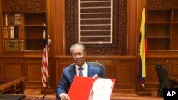FILE - In this March 2, 2020, photo, Prime Minister Muhyiddin Yassin poses for pictures on his first day at the prime minister's office in Putrajaya, Malaysia.