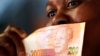 A shopper shows off South Africa's new banknotes, which features an image of former president Nelson Mandela on the front, (File photo).