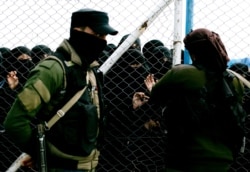 FILE - Women speak to guards at the gate that closes off a section for foreign families who lived in the Islamic State's so-called caliphate, at al-Hol camp, in Hasaka province, Syria, March 31, 2019.