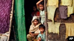 FILE - A Myanmar Muslim family, who identify themselves as long-persecuted “Rohingya” Muslims, look out from their tents at Da Paing camp for Muslim refugees in north of Sittwe, Rakhine State, western Myanmar.